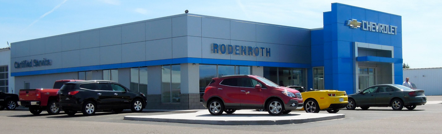 Chevrolet dealership building with various parked cars, including red, black, and yellow vehicles.