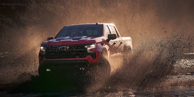 Red Chevy Silverado driving through mud