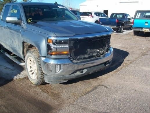 Damaged pickup truck with missing front grille in parking lot