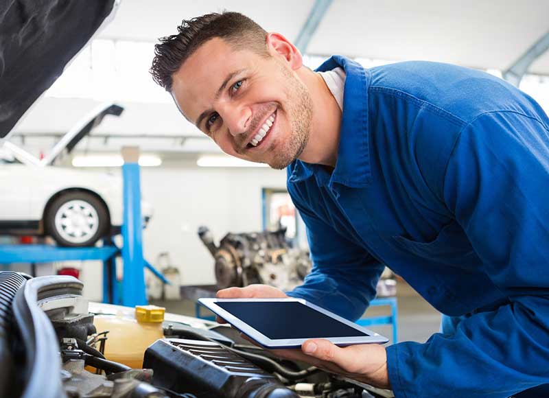 car service mechanic inspecting a car's engine with happy face